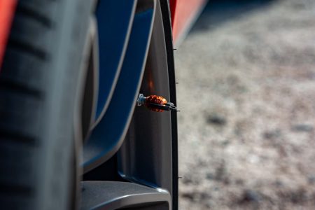 Detailed shot of a car's wheel showcasing an orange decorative tire valve cap on a sunny day.